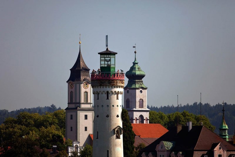 Der Leuchtturm im Hafen von Lindau wird umrahmt von den beiden Kirchtürmen